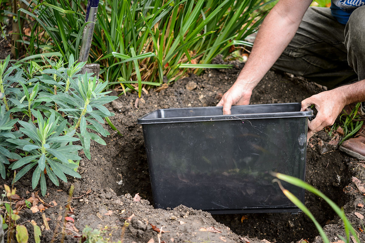 A container being inserted into a hole in the ground