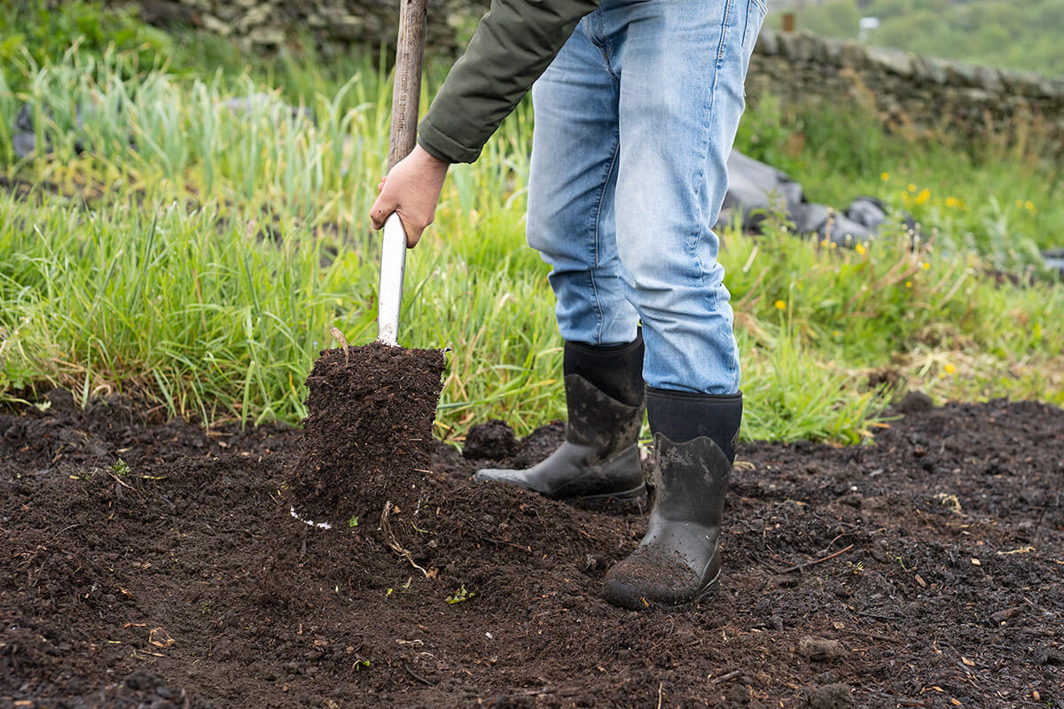 Compost being spread by a large metal shovel
